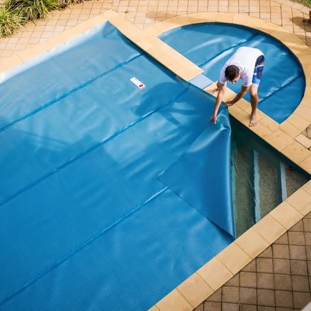 Craig fitting a solar pool cover onto an in-ground pool